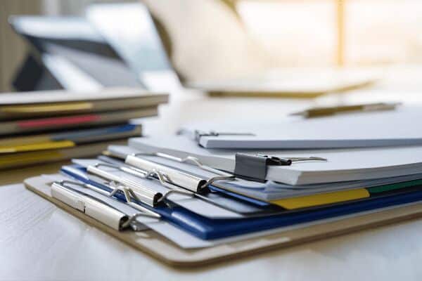 A pile of clipboards hold Southpacs tips to make documenting for your QMS easier, more effective and value-adding.